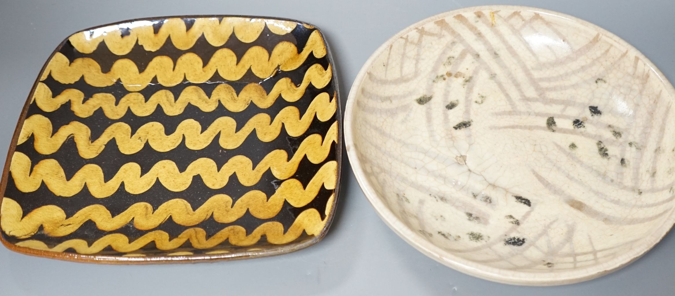 British studio pottery; Doug Fitch (b.1964), a moulded square platter with brown and yellow slip trailed decoration, 27cm wide, together with a Peter Clough (b.1944) crackle glaze dish, 29cm diameter, (2)